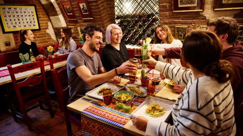 Freundesgruppe stößt gemeinsam mit Cocktails bei leckerem Essen im Restaurant Don Quichotte im Europa-Park an.