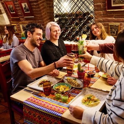 Freundesgruppe stößt gemeinsam mit Cocktails bei leckerem Essen im Restaurant Don Quichotte im Europa-Park an.