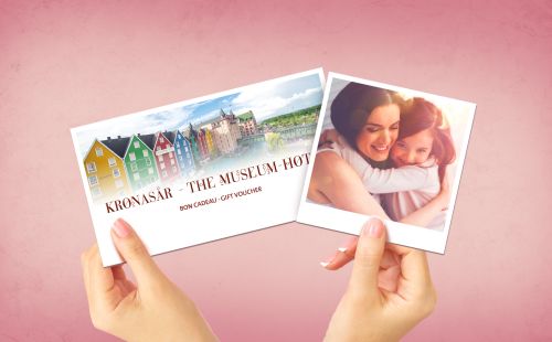 Mutter hält Tochter im Arm und ein Übernachtungsgutschein sieht man im Hintergrund