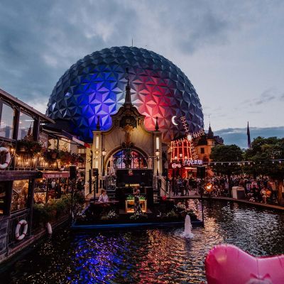 The atmospherically decorated French themed area during the Summer Night Party at Europa-Park. The dome of the Eurosat – CanCan Coaster ride is illuminated in the French national colours.